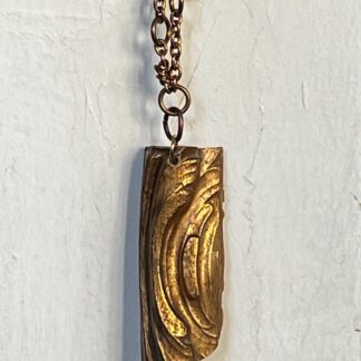 vintage gold colored piece with swirl design on brass chain