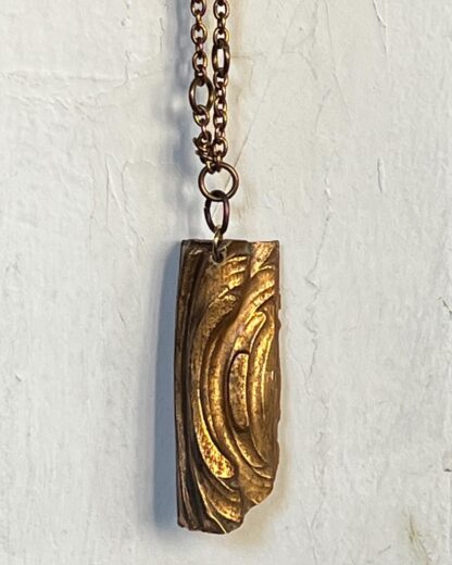vintage gold colored piece with swirl design on brass chain